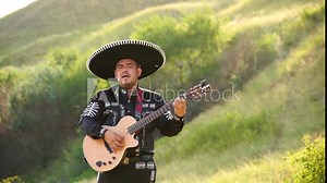 Mexican musician mariachi in traditional costume with sombrero plays guitar.
