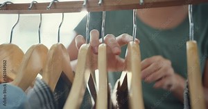 Beautiful attractive Asia lady choosing clothes on clothes rack dressing looking herself in mirror in living room at house. Girl think what to wear casual shirt. Lifestyle women relax at home concept.