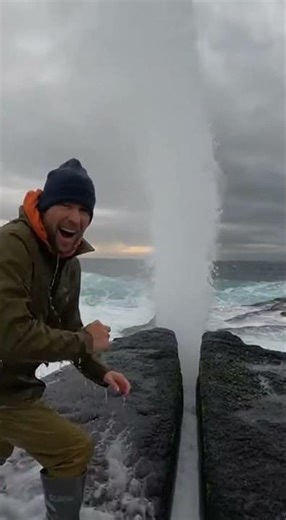 Wave Explosion Drenches Man on Rocky Shore