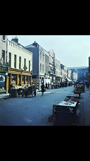 Moore Street in the 1950s – The Beating Heart of Dublin Step back to the Dublin of the 1950s and you can almost hear them: the legendary Moore Street dealers roaring their lungs out from dawn till dusk. “Apples! Six for a shillin’!” “Get yer fresh cod, straight off the boat this mornin’!” “Any oul’ rags, any oul’ iron?” The air was thick with steam from braziers roasting chestnuts, the sweet smell of oranges piled high in pyramids, and the unmistakable whiff of fresh fish laid out on marble slab
