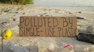 Polluted by single-use plastic sign on a littered beach, marine pollution and debris, ocean conservation
