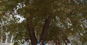 A group of college students enjoys a discussion and laughter while sitting on park benches, embodying friendship and informal education. Faculty colleagues engaged in subject or random discussions.