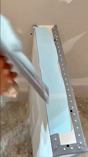 Carefully Spreading Light Blue Joint Compound Over Drywall Edges To Create Smooth Walls