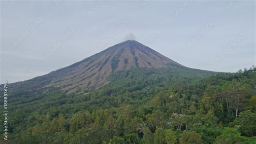 Cinematic drone sliding left movement showing the symmetrical peak of Mount Inerie volcano above a dense green jungle in Bajawa.