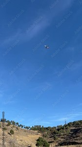 Vertical 4K video. Plane flies through sky over hill and mountain with a forest. The plane from the blur becomes clear. The concept of adventure, travel, flight, aerophobia. Transport. Air travel