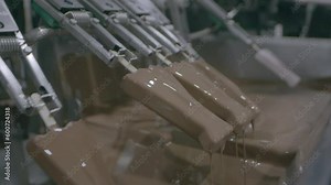 Food production assembly line dipping ice cream lollies into melted chocolate