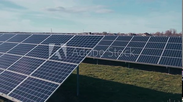 Photovoltaics solar panels in a solar park. Solar panels on green grass and blue sky. Solar panels system power generators. Alternative power energy concept.