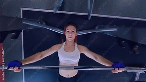 Woman in the gym trains on bodybuilding machines. A woman pumps her muscles on a simulator. Training of the female body on a sports machine.