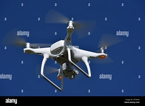 A view from below of a flying DJI Phantom 4 Drone  with a gimbal and camera attached.  Drone, photography, video, flying, surveillance Stock Photo - Alamy