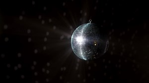 Disco Ball with Reflected Moving Rays Rotating. Mirror disco ball in white light. Isolated disco ball on black background. Close-up. Mirror ball spinning indoors. Performance. The reflection of lights