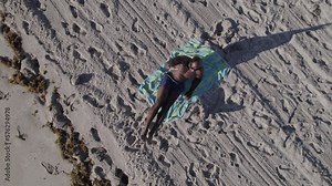 Muscular male athlete doing toe touch sit ups on a sandy beach, aerial overhead footage