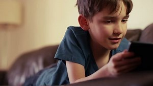 clip-9081299-young-boy-using-tablet-while-lying-down