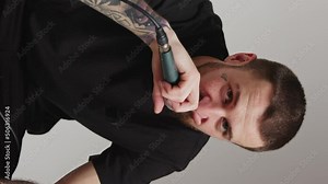 Vertical studio shot of a middle-aged tattooed creator musician rapping to his microphone and looking at camera. Giving the microphone to the audience to sing with him. High quality 4k footage