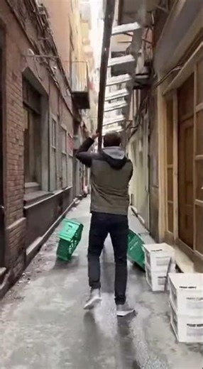 Man Struggles with Huge Ladder in Narrow Alley – Chaos Ensues!
