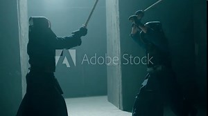 Japanese kendo fighters with bamboo swords competing in the fog in dark mystic industrial building . Epic battle video with two kendo fighter . Shot on ARRI Alexa Cinema Camera in slow motion .