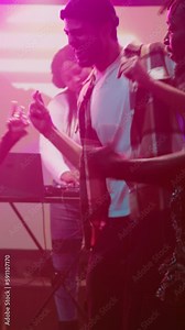 Vertical video: Group of people dancing at disco party, having fun together with breakdance battle at club. Friends showing off funky moves for dance battle on dance floor, partying in discotheque.