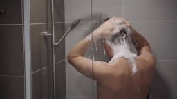 alone man is taking a shower in bathroom, use shampoo