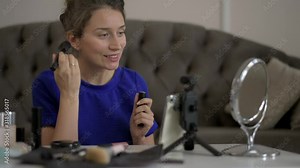 Woman vlogging on mobile phone, presenting and reviewing cosmetics accessories and products online