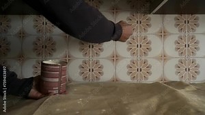 Painting old tiles Painting, repainting old outdated kitchen ceramic tiles on back wall with modern chalk paint indoors at home. We give an old kitchen a new look. The hand holds a brush.