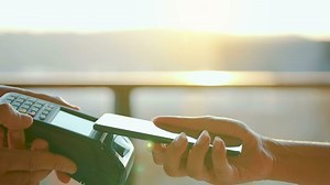 Close-up, man using smartphone cashless wallet NFC technology to pay order on bank terminal. Card machine in female hand
