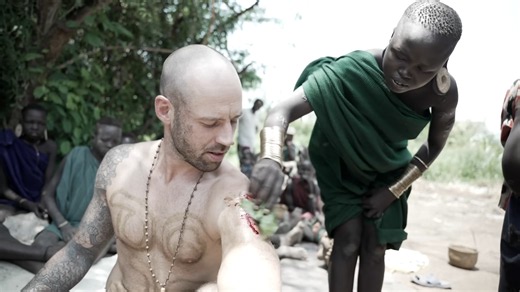 Guy gets prehistoric tattoo by being repeatedly stabbed and smeared with poop