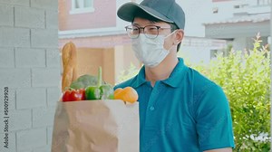 Food Delivery concept. Asian delivery man hand giving bag of food, fruit, vegetable delivery to costomer grocery delivery service.