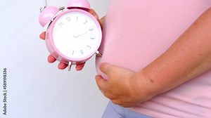 middle-aged pregnant woman holds alarm clock near her belly close-up, waiting for newborn, concept of prenatal contractions, pregnancy reproduction, Pregnancy rate, happy motherhood, selective focus vídeo de Stock