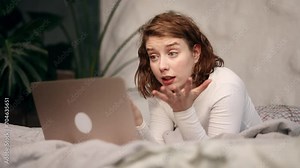 Irritated arguing young woman yelling at laptop computer while laying on bed at home Angry nervous female talk by video call expressing negative emotion Bad conflict working or personal conversation