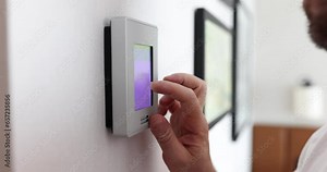 Person changes temperature in big apartment with wall control panel. Homeowner who wants to cool room on hot day slow motion