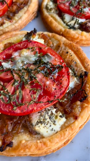 Trent on Instagram: "Ina Garten’s Tomato & Goat Cheese Tarts were recipe number 14 of the project, and while I LOVED them, I somehow never revisited them … until now! Why did I wait so long!? Circles of buttery, store-bought puff pastry get a sprinkle of Parmesan, a pile of almost caramelized onions, and creamy dollops of garlic-herb goat cheese. They’re topped with juicy slices of tomato, drizzled with olive oil, and showered with shaved Parmesan and ribbons of basil. It’s a deceptively simple 