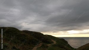 This footage reveals the rugged beauty of Cap Gris-Nez as a pathway winds along the cliff's edge, overlooking the English Channel. The brooding sky and the beam of light on the horizon evoke a