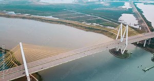 Aerial View Over a Cable-stayed Bridge Crossing over the Houston Ship Channel. Drone footage of the Fred Hartman Bridge connecting Houston and Baytown. Orange teal color grading. Wide angle.