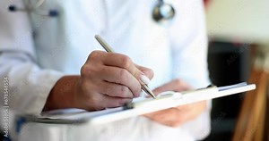 Female doctor nurse practitioner writing patient information. Cardiologist writing prescription in paper notepad and working with medical documents in clinic