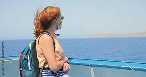 Girl with red hair traveling on the Gozo Channel Line ferry from Malta to Gozo Island, looking towards the front of the boat over the Ocean.
