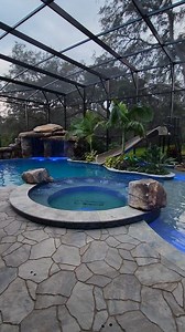 This backyard has a huge grotto, a waterslide, a big spa, a swim-up bar, a screened enclosure, a fire pit, and a lifeguard stand. #insanepools #lucaslagoons #pool #poolbuilders #backyard #luxurylife #waterslide | Lucas Lagoons