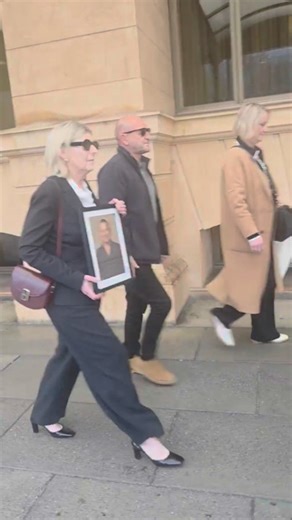 Andrea Farrell leaves court holding a photo of her partner Robert Pinto