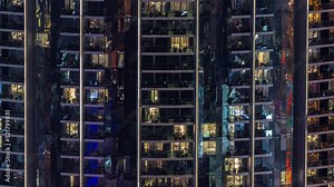 Illuminated panoramic windows in apartments of a high class building at night timelapse. Many glowing lights in skyscraper