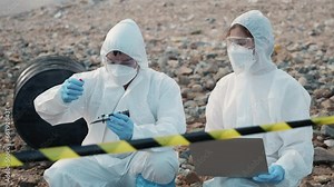 Ecologist sampling water from the river to water quality tester and peek into, Biologist wear protective suit and mask collects sample of waste water from industrial for pH meter, problem environment
