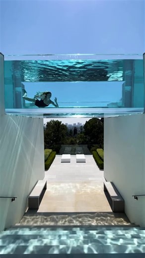 McClean Design on Instagram: "A hillside pool designed to be experienced in motion. This 1,200-square-foot infinity pool stretches across the landscape, featuring a transparent glass bridge that spans a grand stair below—casting shifting light and reflections as swimmers pass overhead. Blurring levels and dissolving boundaries, the pool connects terraces, gardens, and city views into a single continuous experience of water, light, and architecture. #McCleanDesign #GlassPool #PoolBridge #LuxuryPo