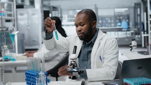 Lab assay development specialist investigating blue liquid polymer properties in test tube container. Molecular biologist testing new synthetic material durability and viscosity in lab, camera B