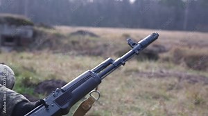 Machine gun barrel. Soldier shooting from a machine gun on a shooting range, close up. Soldier with a machine gun on a military firing range shooting at a target. Concept of war, army and military.