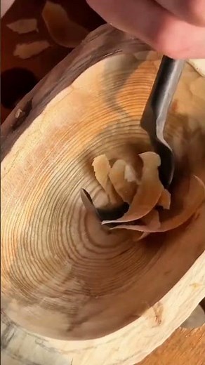 Carving wooden bowl using a traditional curved gouge tool to shape the smooth interior surface area