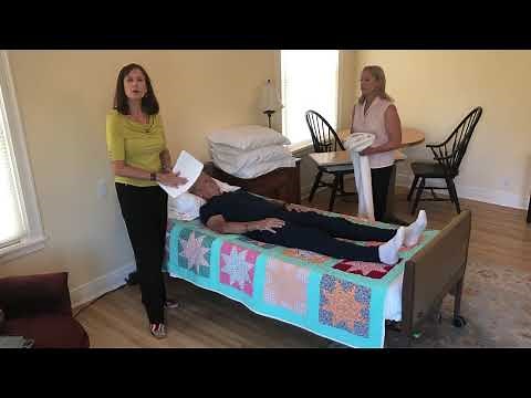 Demonstration on 1 person placing a turn or draw sheet under a patient.