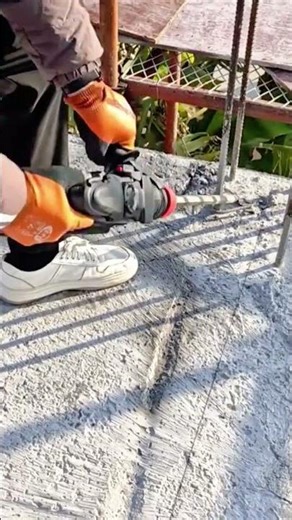 using a heavy duty red power drill to create deep holes in a hard concrete surface for construction