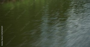 Looking over side of speeding jet boat at water passing by. Shoreline reflecting in water.