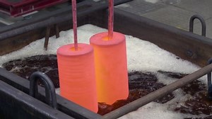 金属製品の硬化。 熱い金属を炉から取り出し、焼入れ液中に降ろす。 金属加工工場。 接写