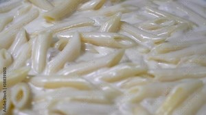Close up shot of pasta getting cooked on a pan with sauce and bubbles popping up due to heat.