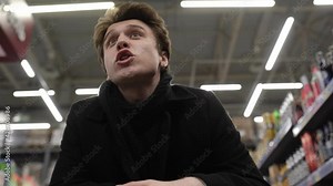 An angry man is standing in line at a supermarket with a cart