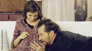 Young woman and man talking to child in pregnant belly laughing