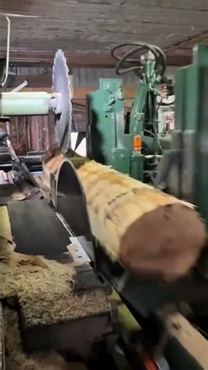 Cutting large log into planks using massive circular sawmill blade in industrial woodworking facilit